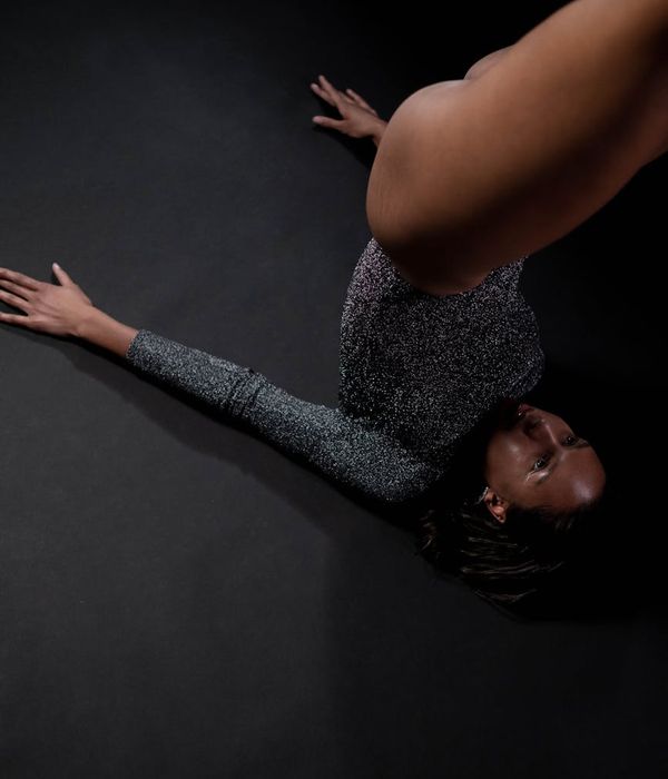 Person performing gentle stretching movements in a dark studio